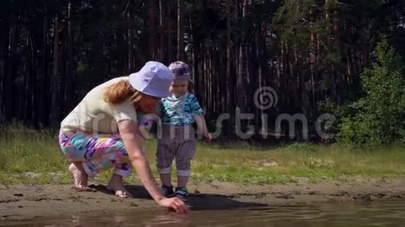 妈妈和她的小儿子在日子里妈妈和她的小儿子在森林湖的岸边玩水视频的预览图