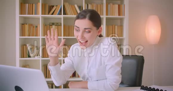 一位年轻迷人的高加索女商人的特写肖像她在笔记本电脑上打了一个视频电话挥手打招呼交谈视频的预览图
