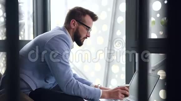 这位30岁长胡子的高技能商人在电脑旁工作时喝着咖啡视频的预览图