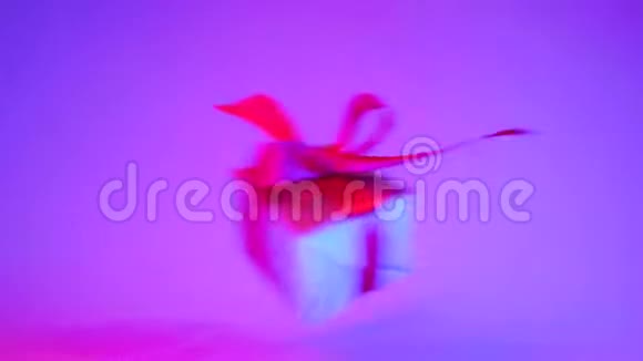 礼品盒与红色丝带从一边到另一边在时尚霓虹灯紫色背景零重力悬浮概念视频的预览图