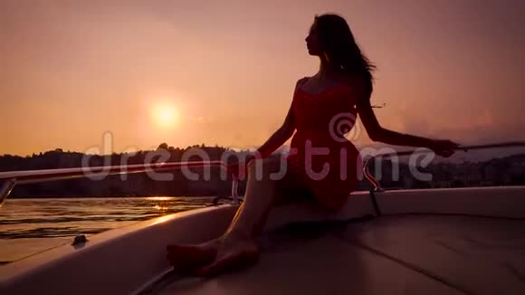 浪漫的年轻女子正坐在日落时分的小游艇上靠在扶手上视频的预览图