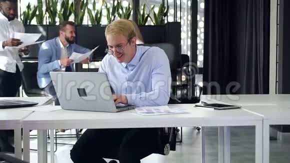 在现代的办公室里在电脑前工作的讨人喜欢的高技能微笑商人动作缓慢视频的预览图
