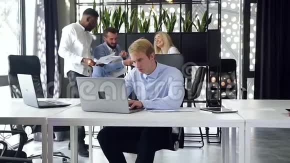 在现代办公室里细心聪明的男性办公室工作人员在工作场所使用电脑的动作缓慢视频的预览图