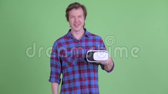 快乐的年轻潮人拿着虚拟现实耳机指着他视频的预览图