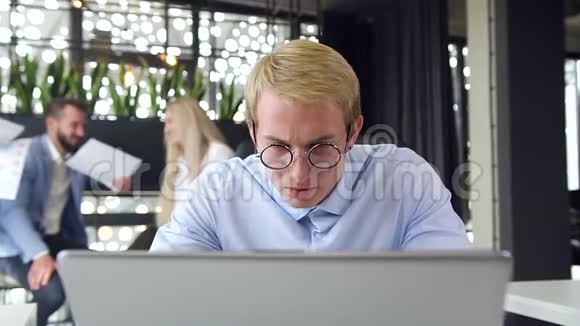 关上忙碌的年轻商人戴着眼镜在办公室的电脑前工作视频的预览图