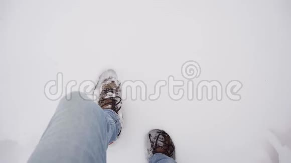 冬季白天穿着牛仔裤和靴子的人在洁白的雪地上行走视频的预览图