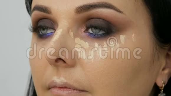 面部轮廓化妆师用刷子引导女人在脸上涂上粉末粉底或遮瑕剂Lilac视频的预览图
