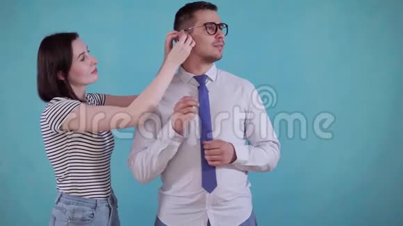年轻女子把助听器放在蓝色背景的快乐男人的耳朵里视频的预览图