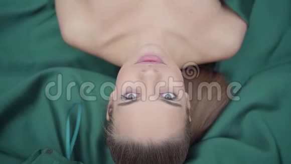 美丽的绿眼睛女孩躺在她惊人的翡翠颜色缎子的下摆的肖像真人系列顶级视频的预览图