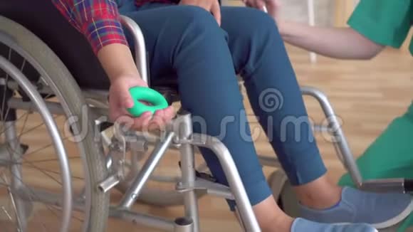 一名年轻女孩在手腕扩张器的帮助下在手部受伤后正在接受医生的康复治疗视频的预览图