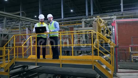 两名男性专家在现代工业设备附近交谈视频的预览图