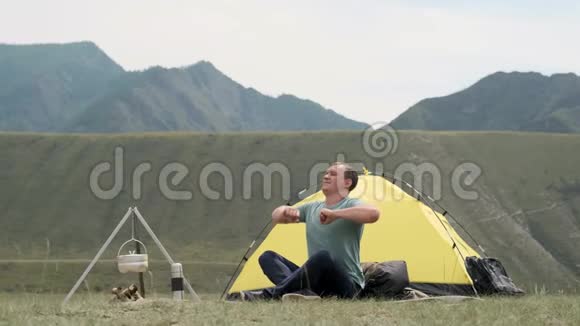 男游客拉着他的双手早上醒来时在帐篷前休息视频的预览图