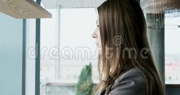 年轻迷人的女性的肖像她看着靠近窗户的办公室上的相机很漂亮的女人关闭视频的预览图