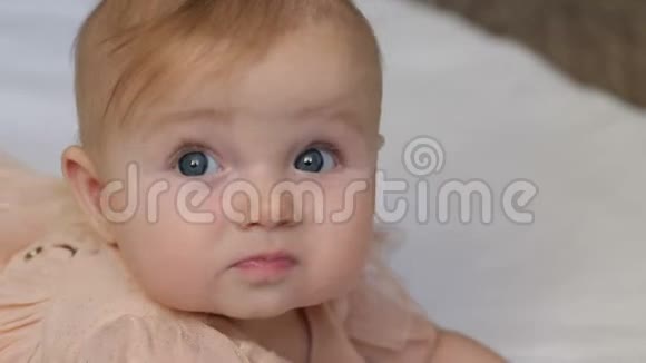 美丽的微笑宝宝一个漂亮的小女孩躺在白色的毯子上用一双漂亮的大眼睛对着相机微笑视频的预览图