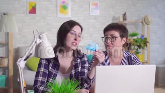 坐在笔记本电脑旁的年轻女子向中年妇女解释如何在互联网上使用银行卡视频的预览图