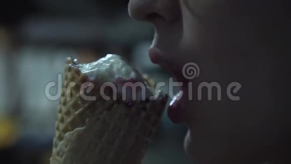 在黑暗中在户外吃冰淇淋的年轻女孩闭上嘴一个女孩吃甜点冰淇淋和草莓果酱视频的预览图