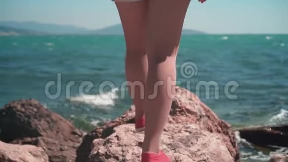 女性腿的特写一个穿红衣服的女孩去海边这个女孩被定位在她的背框里视频的预览图