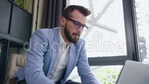 一位英俊体贴的年轻男性办公室经理在电脑前工作在单独的房间里喝咖啡视频的预览图