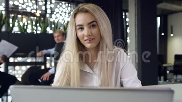 漂亮的年轻快乐的金发商务小姐在办公室里微笑着看着相机显得格外亲切视频的预览图