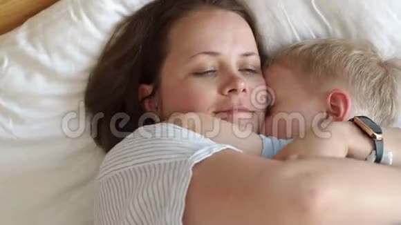 早上妈妈和小儿子在床上的肖像他们醒来拥抱视频的预览图