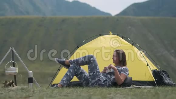 女游客躺在帐篷前手里拿着一杯茶视频的预览图