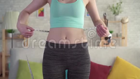 穿运动服装的沮丧的年轻女性使用测量带违反饮食视频的预览图