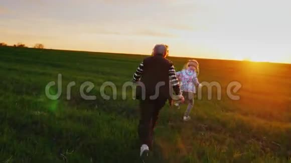 活跃的老年人老妇人和她的孙女在一片绿色的草地上跑来跑去玩狗狗关于视频的预览图