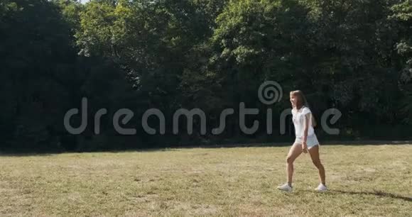 快乐迷人的雌性在夏天在草地上跳跃慢动作视频的预览图