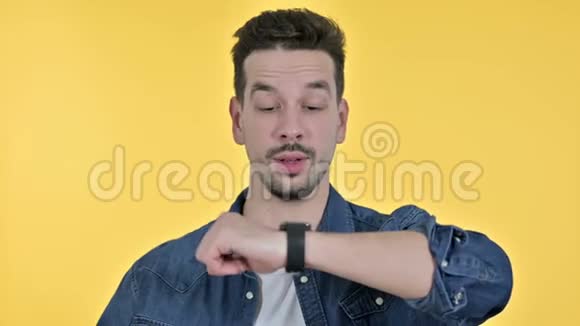 年轻人在智能手表上说话的肖像黄色背景视频的预览图