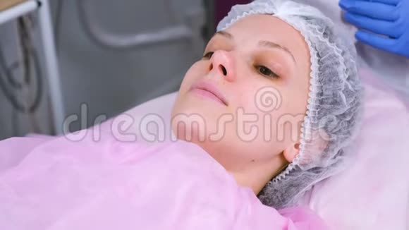 在诊所里戴帽子的女人躺在沙发上接受治疗视频的预览图