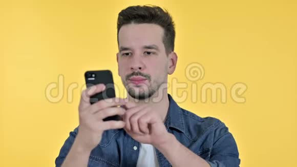 有魅力的年轻人使用智能手机的肖像黄色背景视频的预览图