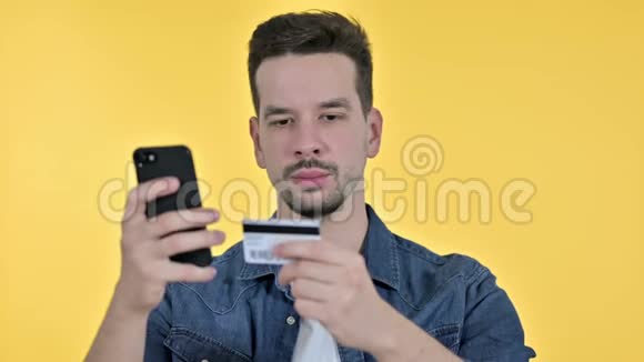 年轻人在智能手机上在线支付的肖像黄色背景视频的预览图