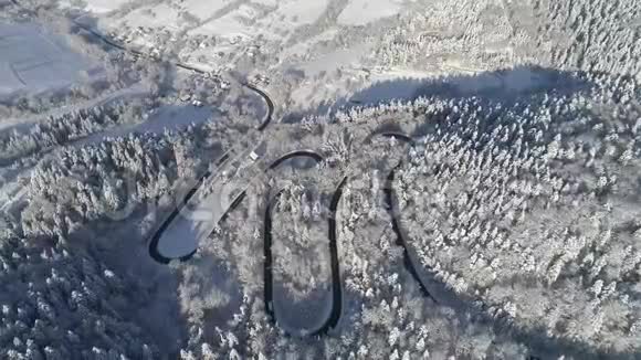 雪山蛇行路上的鸟瞰图白色的房子在冬天的风景视频的预览图