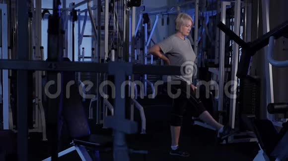 年龄的女人把她的脚向前侧身和向后站在一个站立的位置联合体操复制空间侧视图视频的预览图