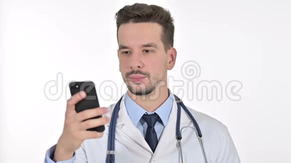 年轻男医生在智能手机上说话的肖像白色背景视频的预览图