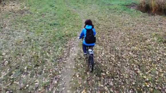 女子自行车骑自行车在秋黄叶公园空中射击运动生活方式鼓舞人心的概念视频的预览图