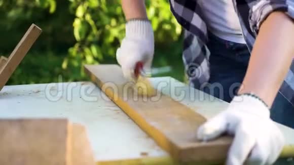 女木工用刷子打磨木板并吹除灰尘视频的预览图