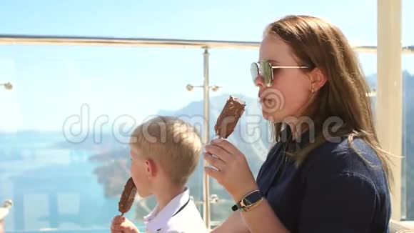 妈妈和儿子在山顶俯瞰大海的咖啡馆里吃冰淇淋视频的预览图