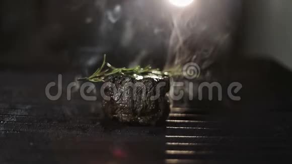 在火里有一串迷迭香的肉它在烤架上煎炸烟雾在背光下升起视频的预览图