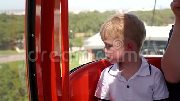 一个小男孩在一个缆车舱上升到一座高山的肖像视频的预览图