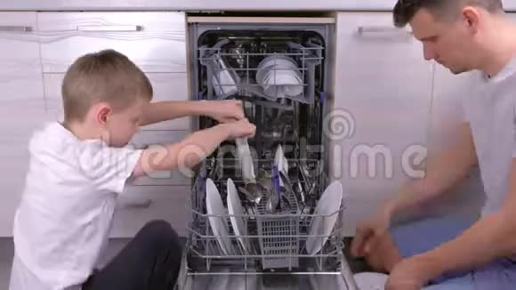 爸爸和儿子正在厨房里把洗碗机里的盘子放在一起视频的预览图