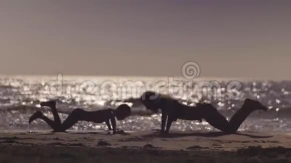 妈妈和儿子在海滩上训练在海附近的推升运动视频的预览图