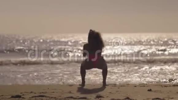 这位年轻女子在海滩上锻炼下蹲视频的预览图