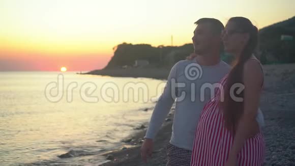 一对年轻的夫妇站在海上日落的背景上一男一女都在笑视频的预览图