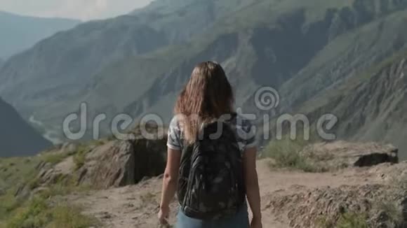 一个带着背包的女旅行者穿过山脉走到山顶视频的预览图