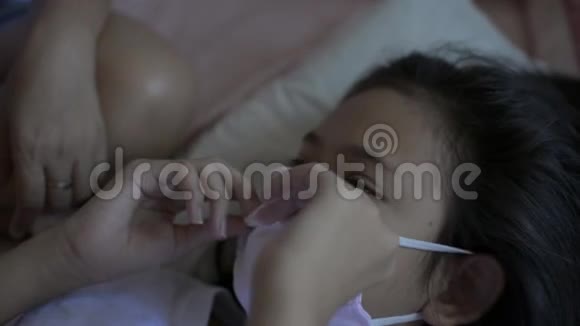 母亲照顾生病的女儿躺在床上在COVID19情况下用温度计测量温度视频的预览图