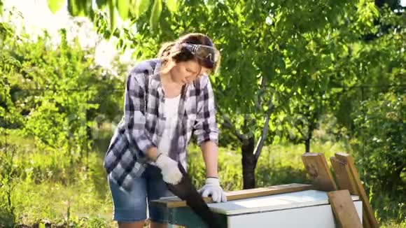白人女性木工在阳光明媚的果园里锯木木板视频的预览图
