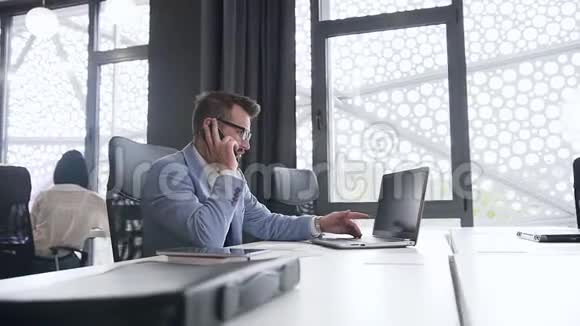 严肃的高技能商人与坐在办公室工作场所的对话者通过电话讨论计算机项目视频的预览图
