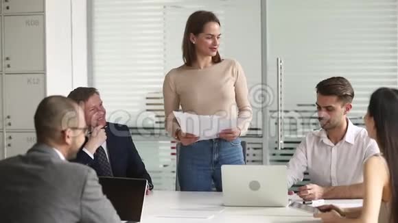 女经理拿着文件和聚集在会议上的员工交谈视频的预览图