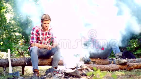 两个帅哥朋友在篝火旁露营游客放松两个朋友伐木工人坐在视频的预览图